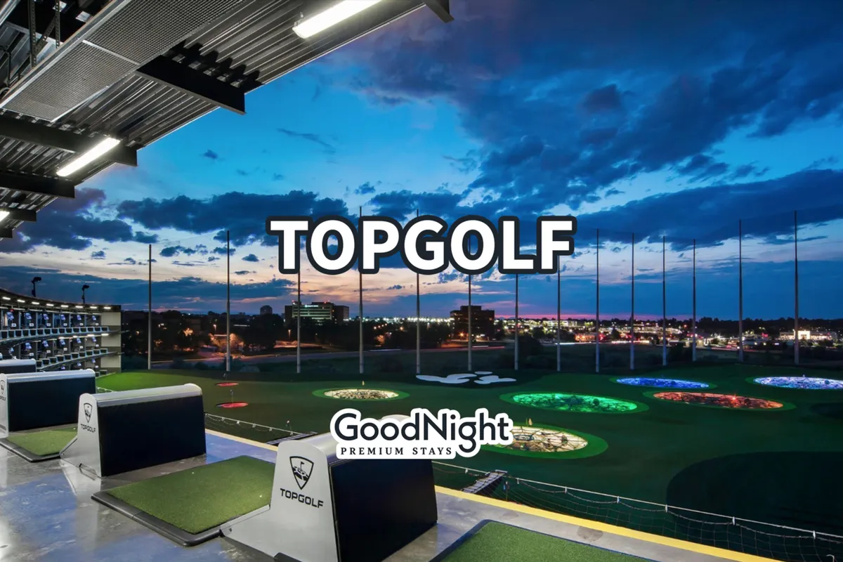 An energetic exterior shot of a golf entertainment venue featuring illuminated targets, bustling golf bays, and the city skyline in the background. People are socializing and enjoying a dynamic group activity, with a lively sunset ambiance.