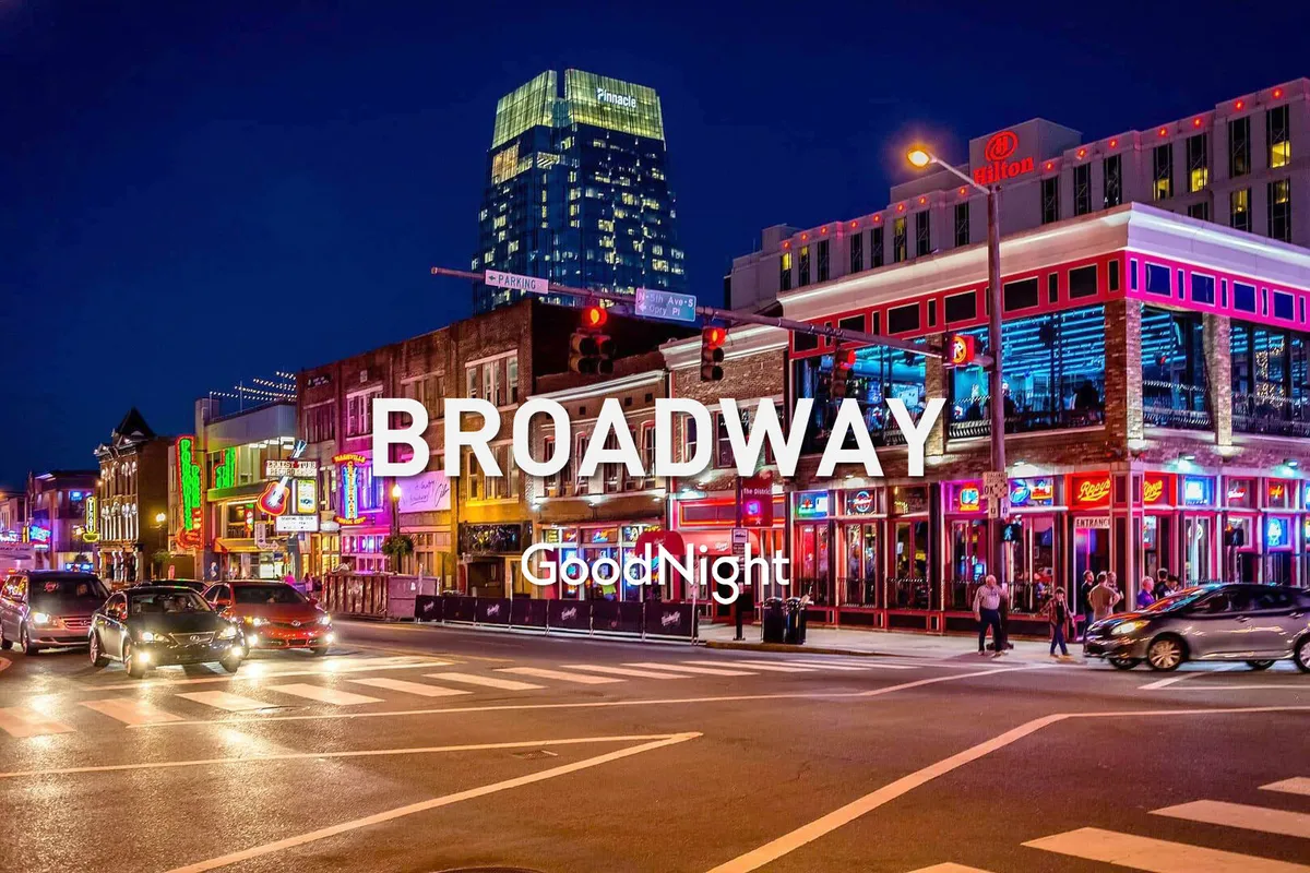 A lively nighttime exterior shot of downtown Nashville, featuring bright neon signs, bustling crowds, and a vibrant street scene. The energy of the nightlife is palpable, evoking the pulse of Broadway's legendary honky-tonks and late-night entertainment.