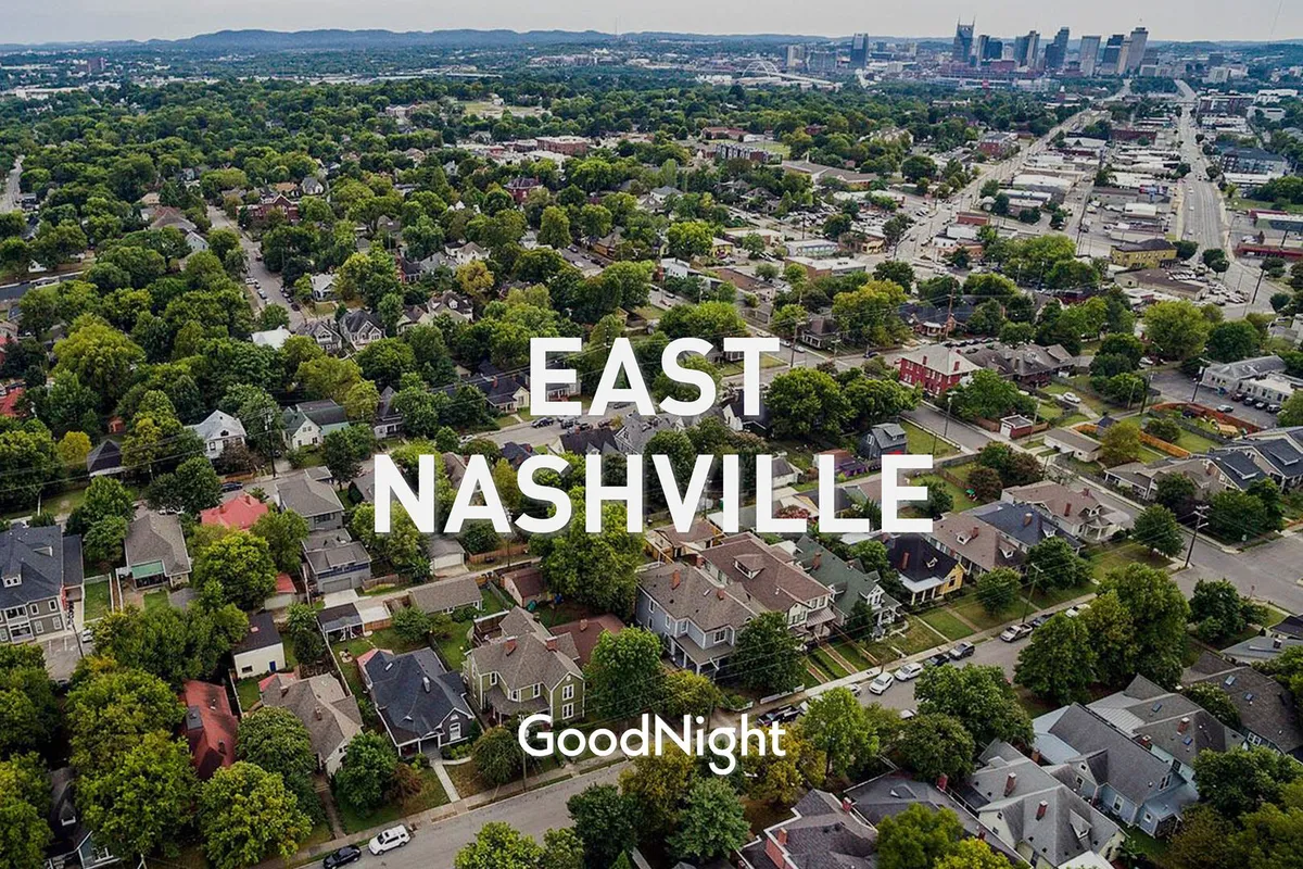 A sunlit neighborhood view with residential homes framed by leafy green trees, the city skyline in the distance, and inviting sidewalks that encourage outdoor exploration. The scene radiates a sense of community, open space, and easy access to local parks and gathering spots.