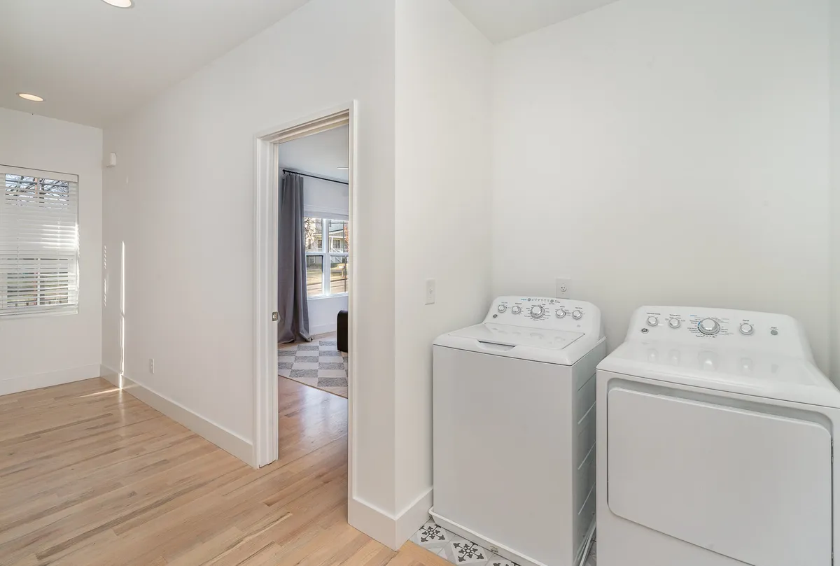 A bright laundry room showcasing a washer and dryer, natural light streaming through a window, and an organized, efficient space for handling laundry needs.